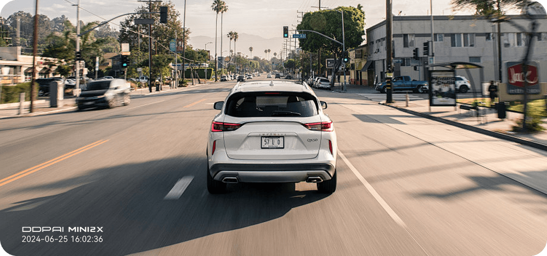 Rear view of a white car driving through a city street, showcasing the clear 2K QHD resolution footage captured by DDPAI MINI2X dashcam.